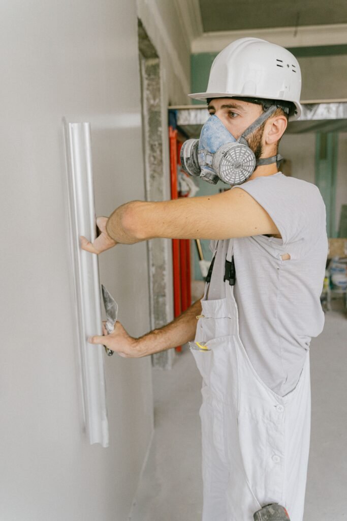 Construction worker smoothing wall with trowel during renovation project.