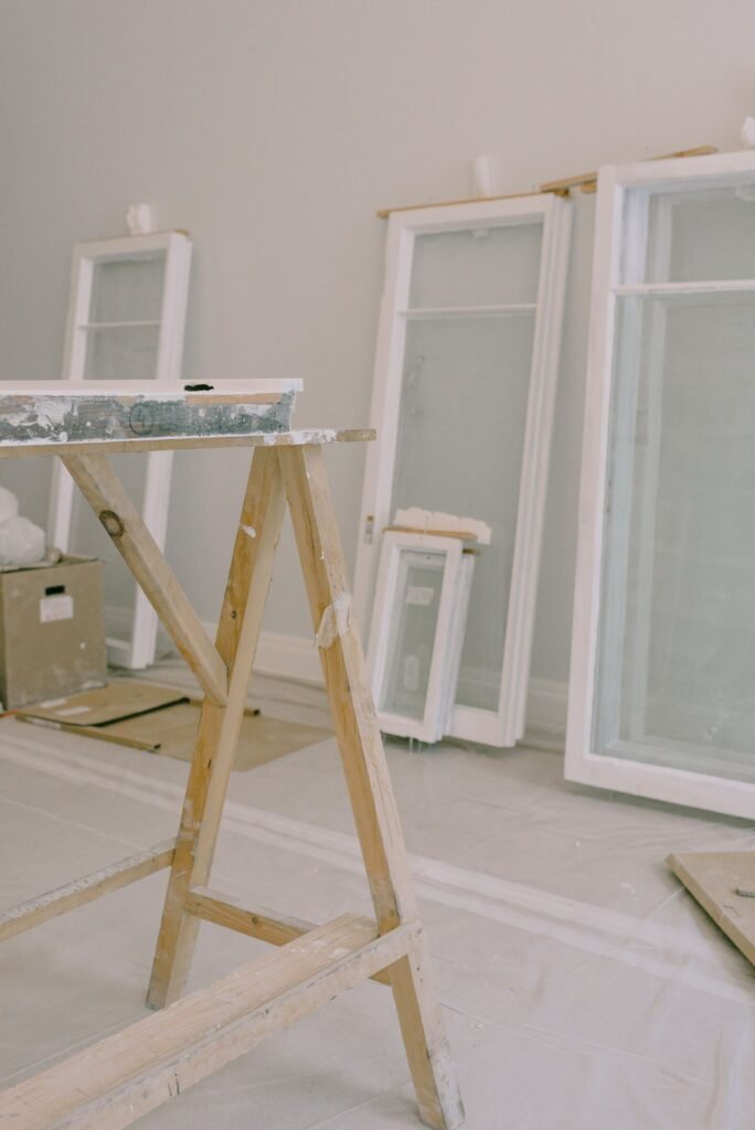 Interior of room with wooden workbench and windows removed from hinges with white frame placed near wall in light room during repair works