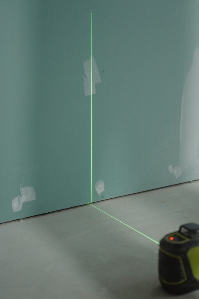Laser alignment tool projecting light on a wall for precise measurement in construction.